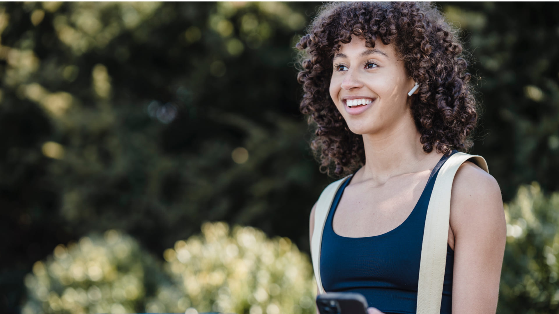 Smiling woman with curly hair outdoors.